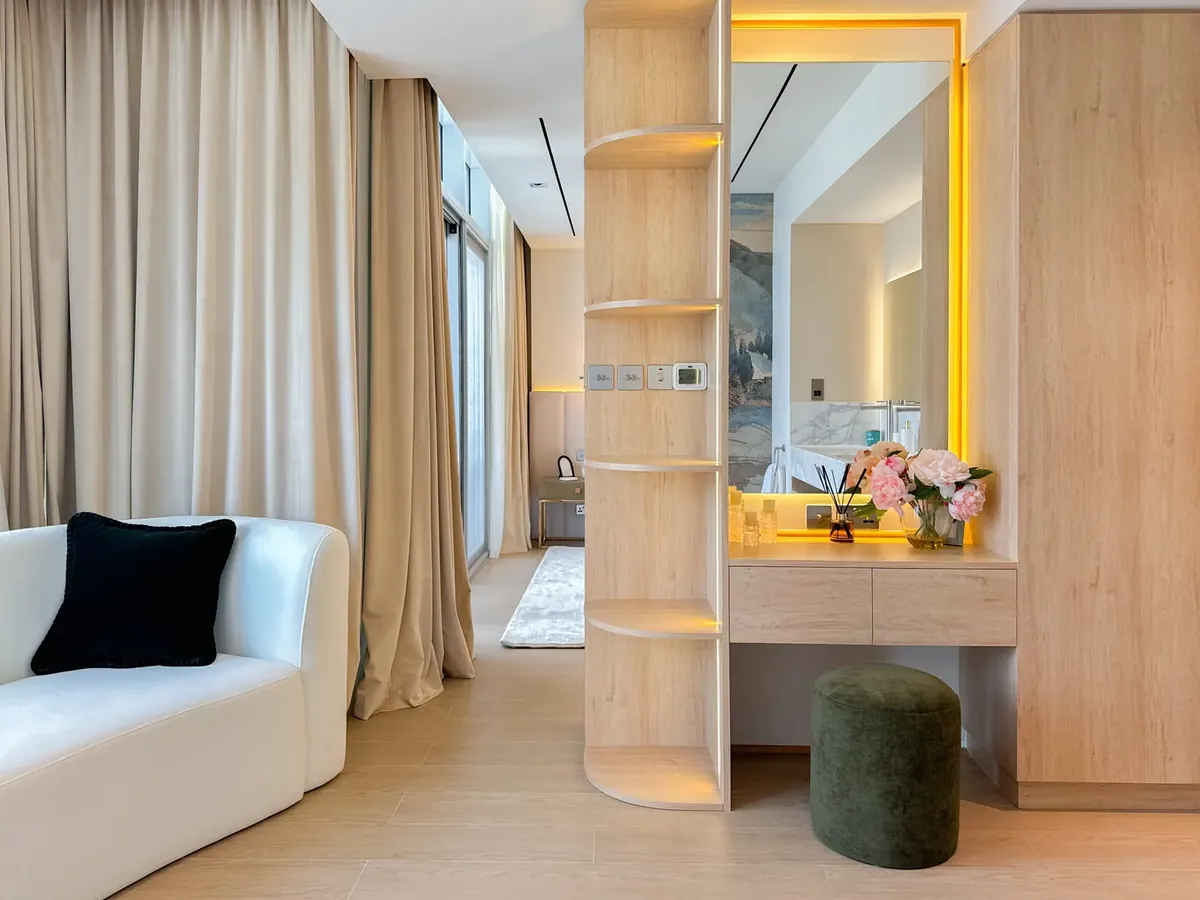 Custom light-oak joinery with a backlit dressing mirror, open shelving and built-in cabinet in a Dubai apartment