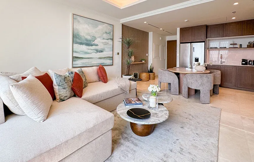 Completed Dubai apartment living room with a cream corner sofa, round coffee table and abstract sea artwork