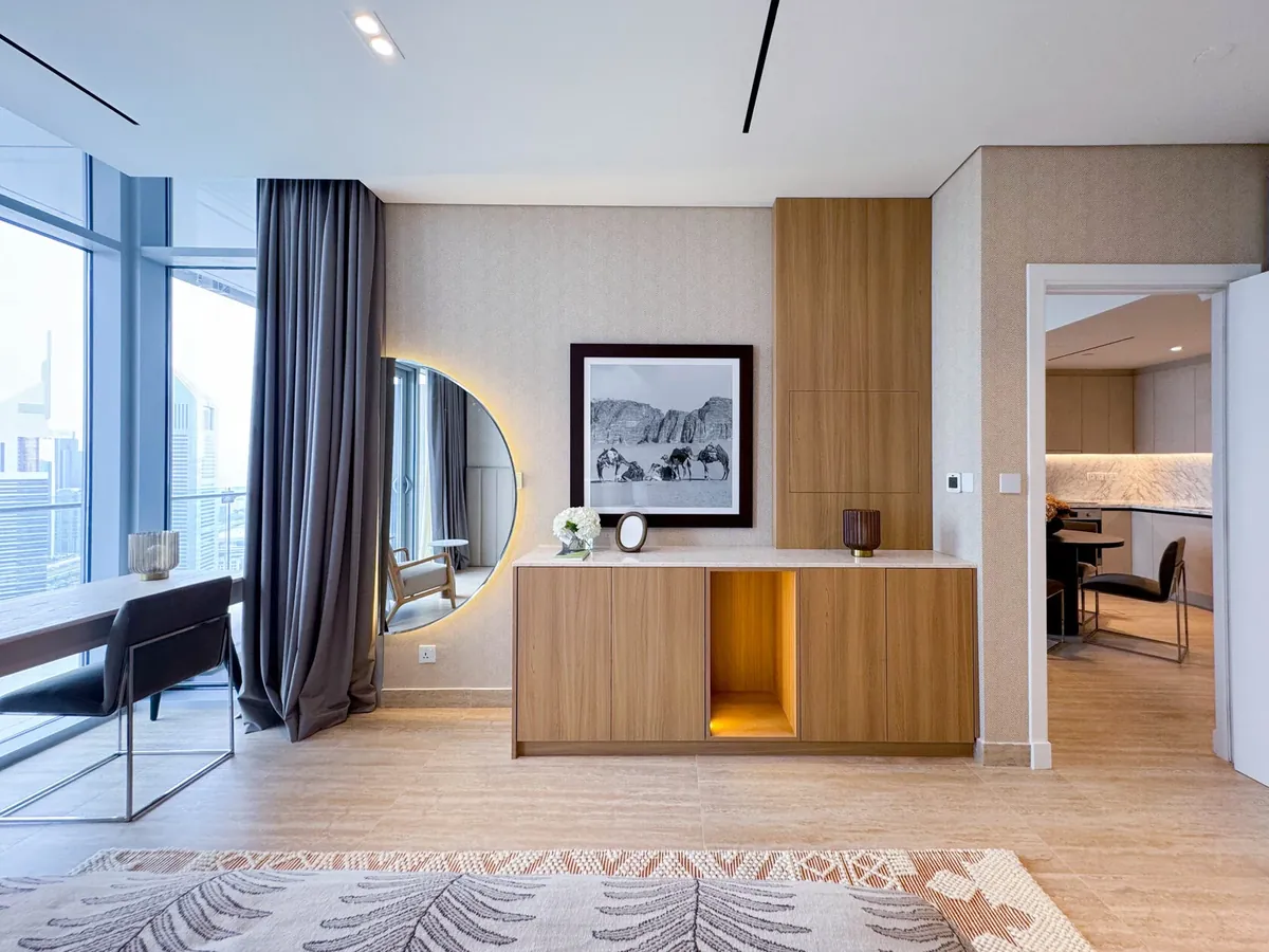 Dubai apartment living area with recessed ceiling lights, a backlit round mirror and floor-to-ceiling windows