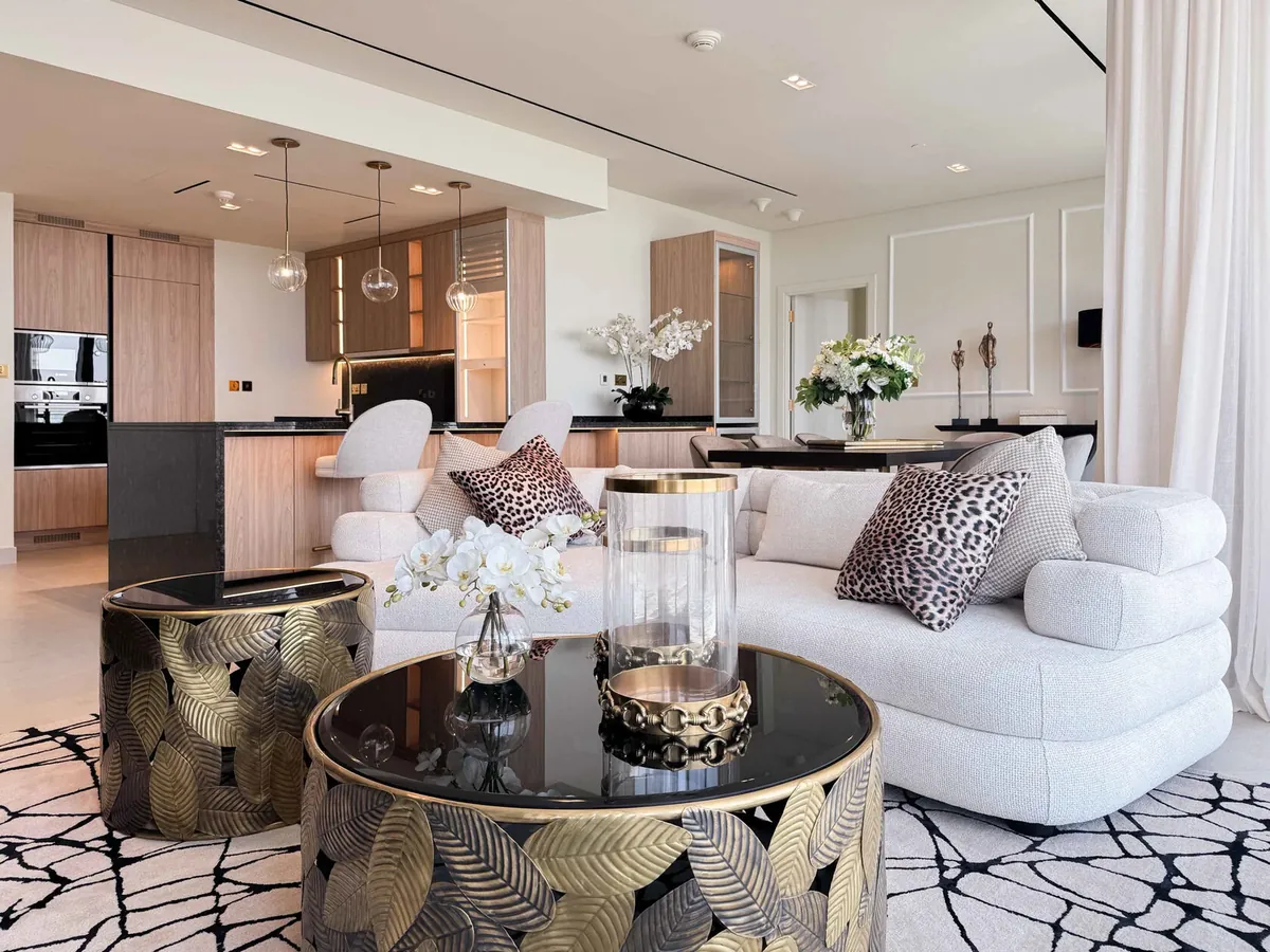 Living room with glass pendant lights over a kitchen island and a cream sofa with decorative side tables